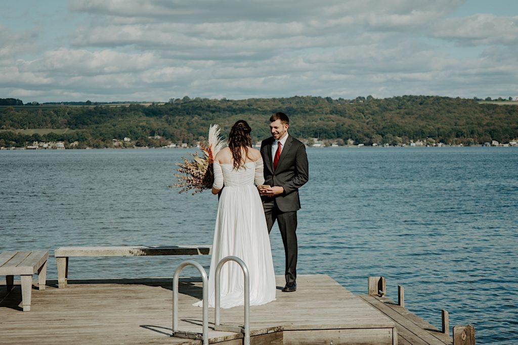 Bride and groom share first look on dock before intimate elopement at the Finger Lakes NY