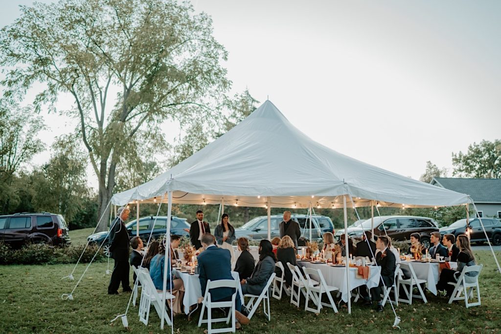Bride and groom celebrate their elopement with their family under a tent
