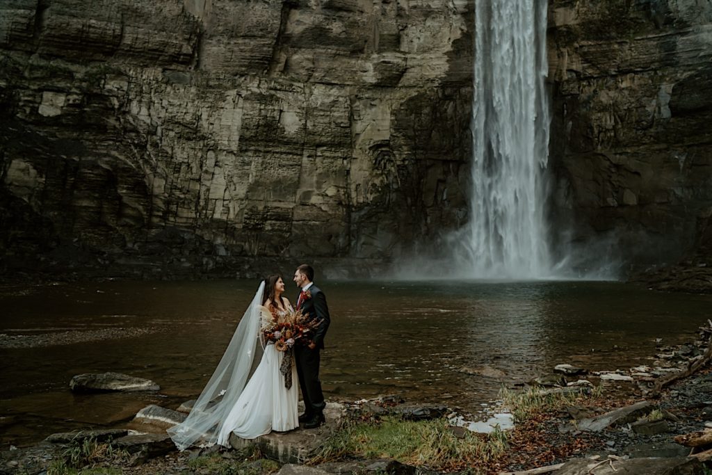 Bride and groom standing in front of water fall for their intimate elopement in the Finger Lakes NY