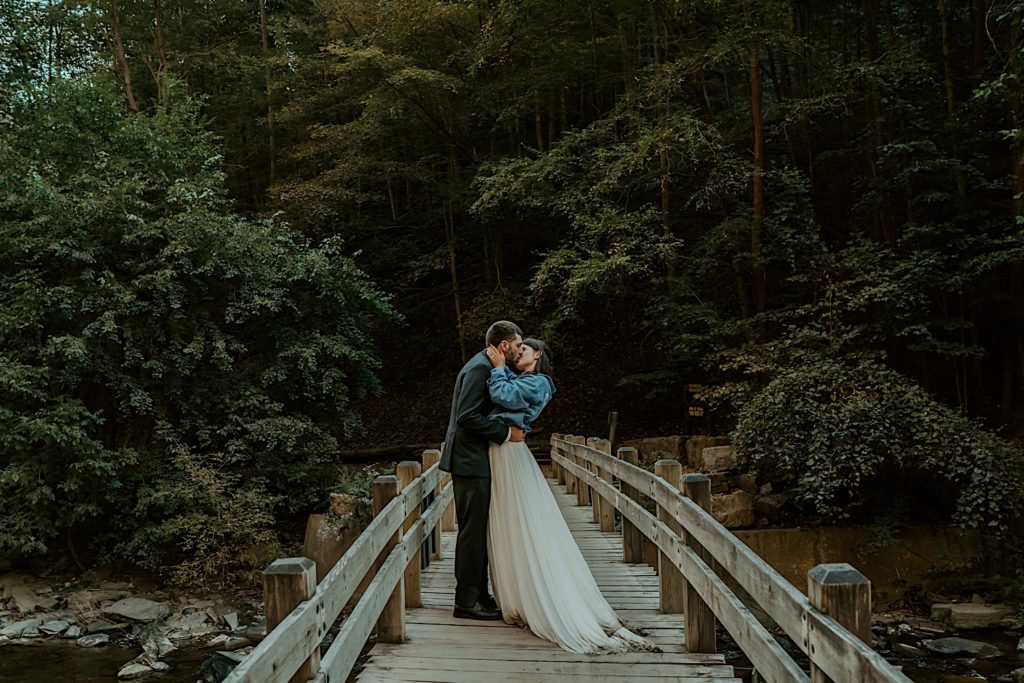 Bride and groom kiss crossing wooden bridge after their intimate elopement in the Finger Lakes NY