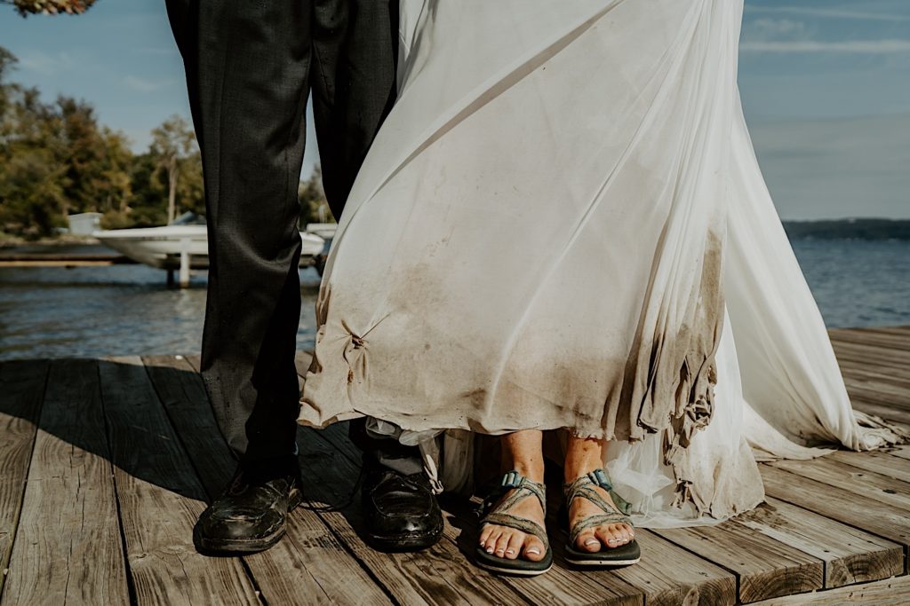 Bride and groom show off their shoes and dirty clothes after an adventurous day for their intimate elopement in the Finger Lakes NY
