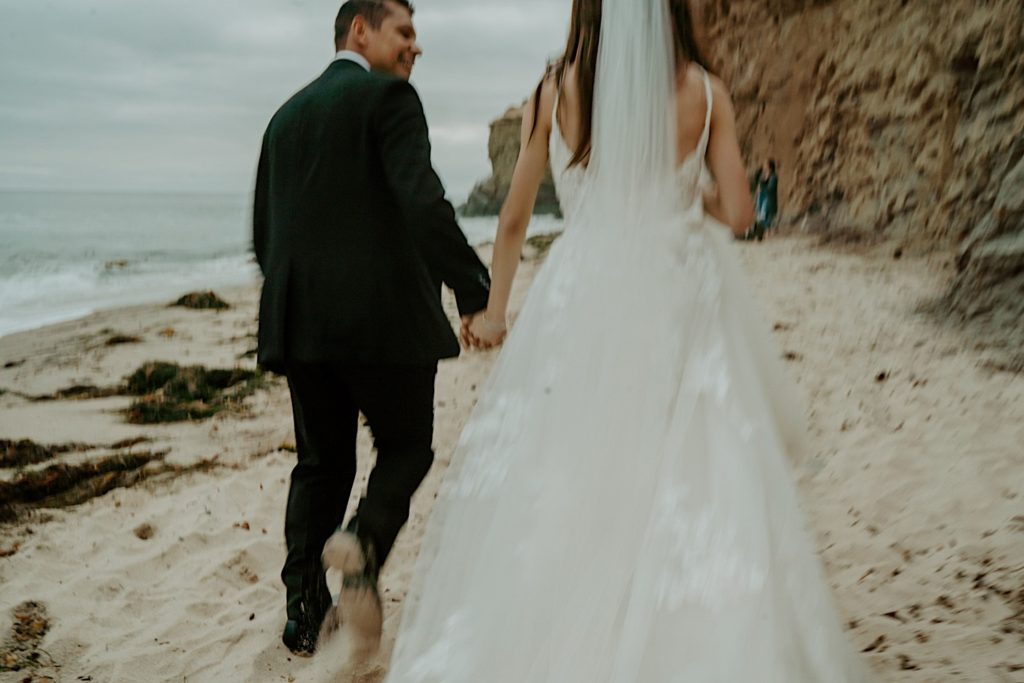 Blurry photo of a bride and groom walking along a beach