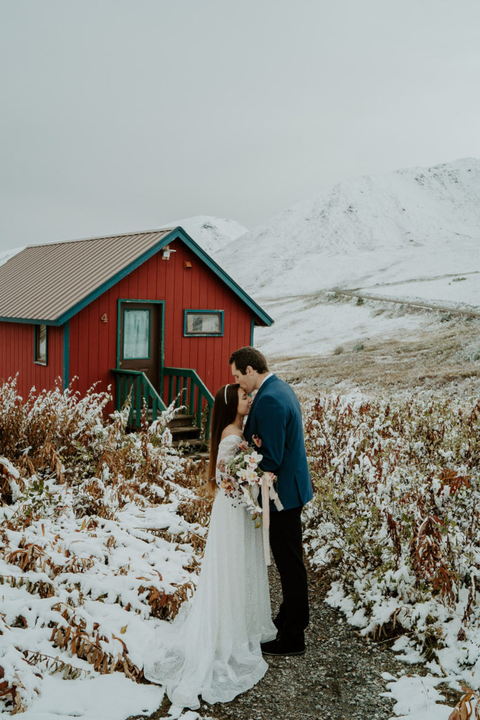 Husband kisses bride's forehead after elopement in Alaska