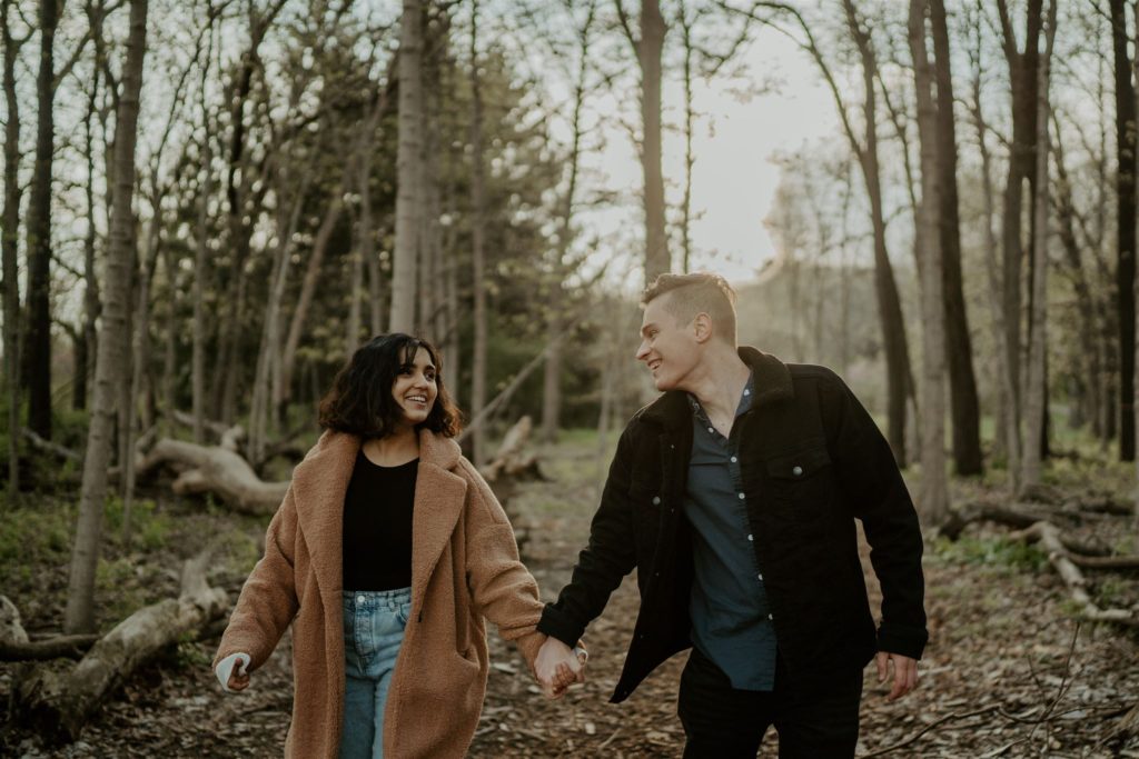Couple looking at each other smiling while walking through a forest