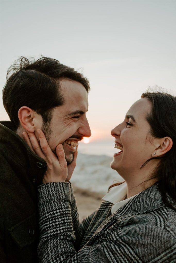 Woman holding boyfriends face while they're both laughing