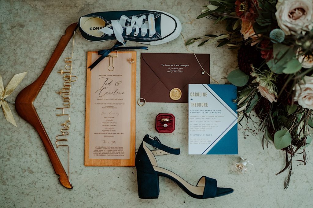Photo of wedding rings, shoes, wedding invites, flowers, and a hanger that reads "Mrs Huntington"