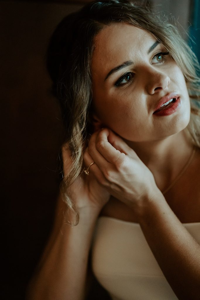 A bride puts an earring on before her wedding