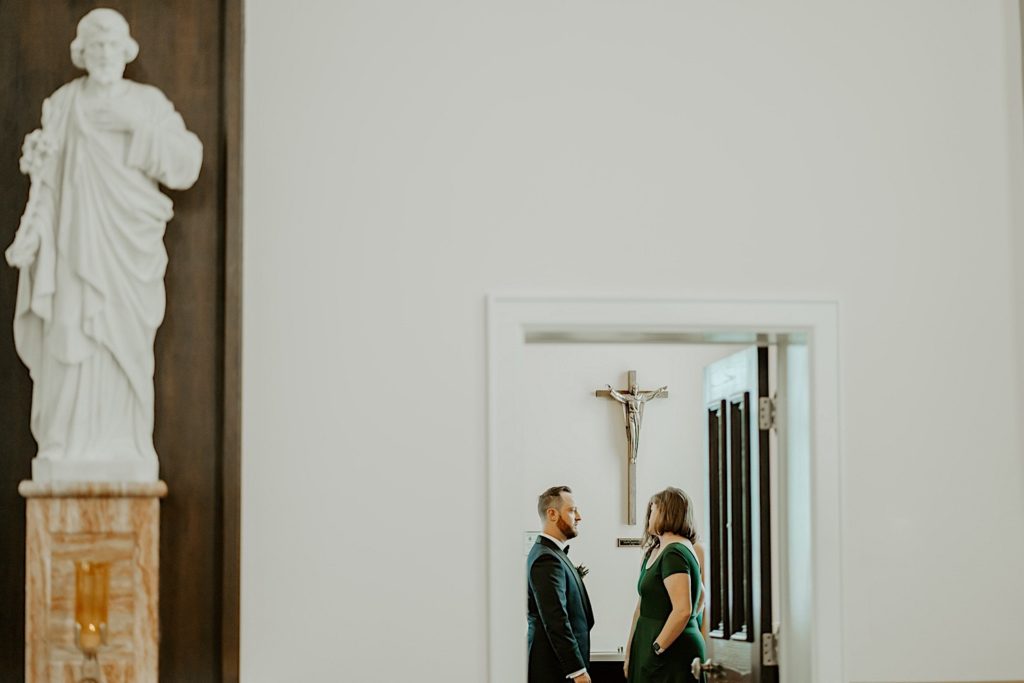 Groom and bridesmaids talking before the wedding ceremony through a doorway
