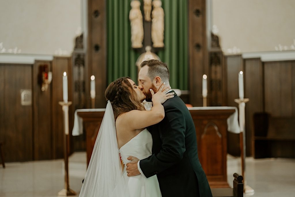 Bride and groom share first kiss inside catholic church after wedding ceremony