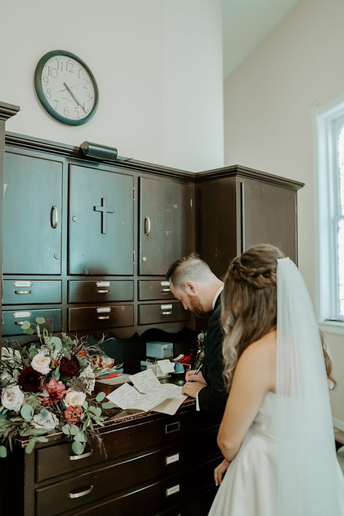 Bride and groom signing their wedding papers in an office of the church