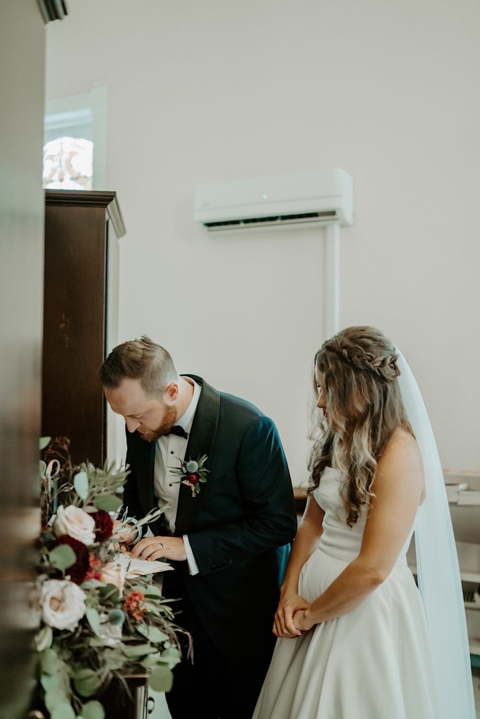 Bride and groom signing their wedding papers in an office of the church