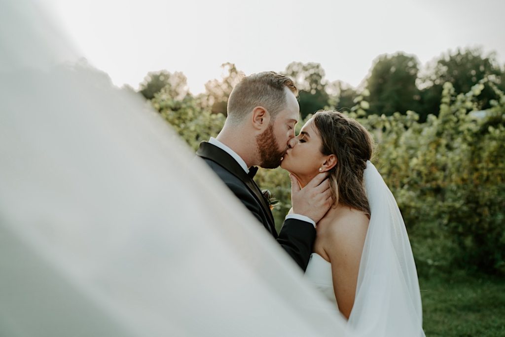 Bride and groom kiss before their wedding reception with a Michigan Winery in the background