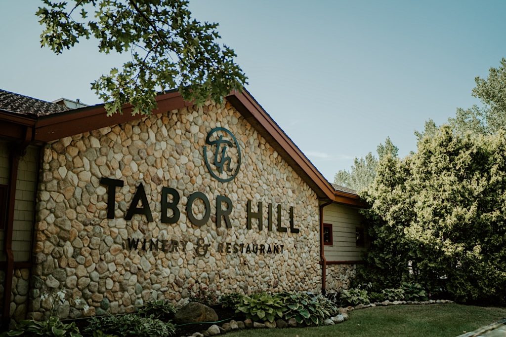 A building with a stone wall that reads " Tabor Hill Winery & Restaurant"