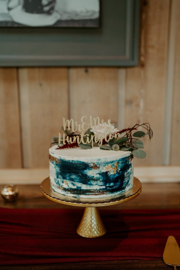 A blue white and gold cake sitting on a table with the words "Mr & Mrs Huntington" on top of it