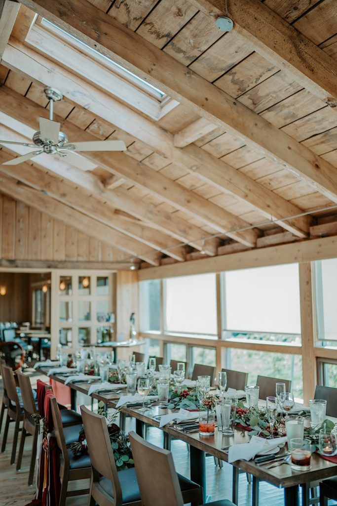 A table decorated with flowers, candles, glasses and plates for a wedding reception in a wood room