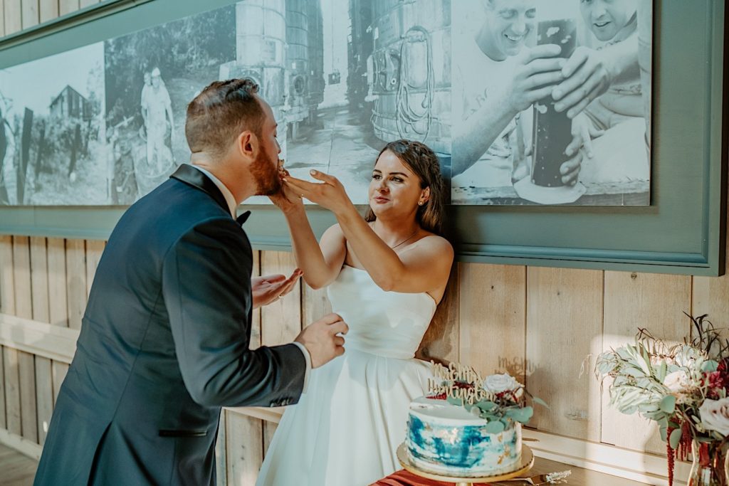 Bride feeds groom a piece of their wedding cake as she smiles