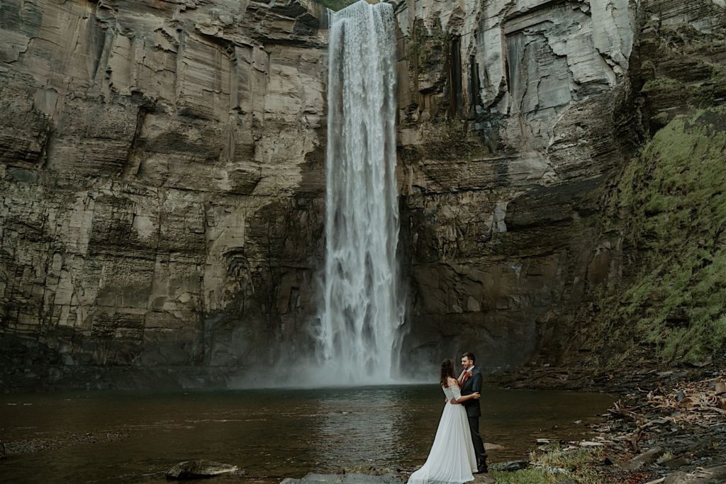 Bride and groom standing with each other with a waterfall in the background