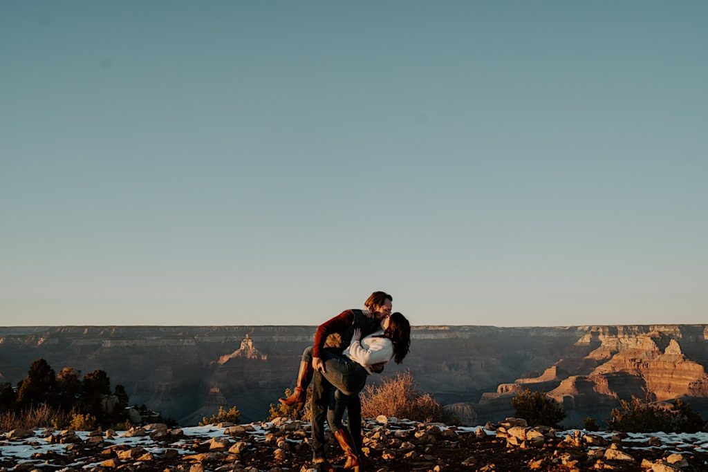 At the Grand Canyon a man kisses and dips a woman with the canyon in the background