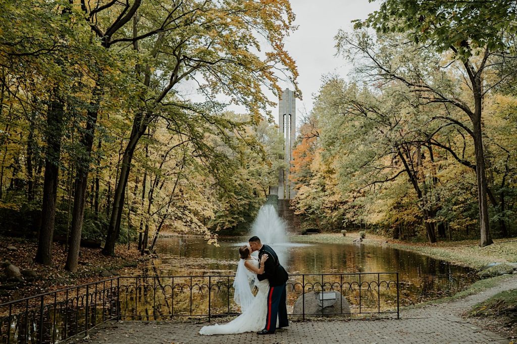 Bride and groom kissing in front of a fountain in a park in Indiana
