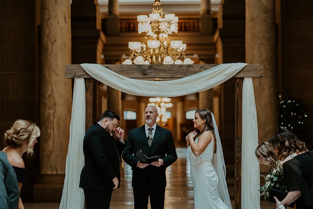 Bride and groom standing next to their pastor during their wedding ceremony at the Indiana State House