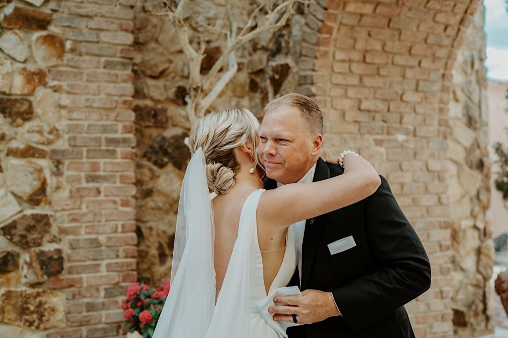 A father and his daughter hug after he sees her in her wedding dress for the first time