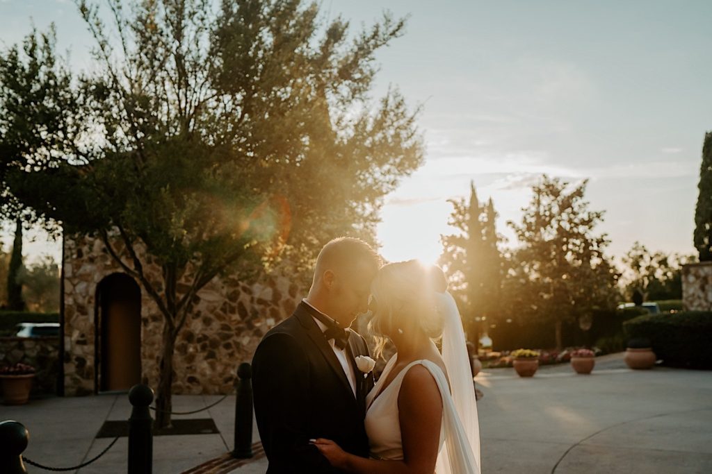 A bride and groom stand under the sunset and press their foreheads against one another after their intimate wedding ceremony at Bella Collina in Florida