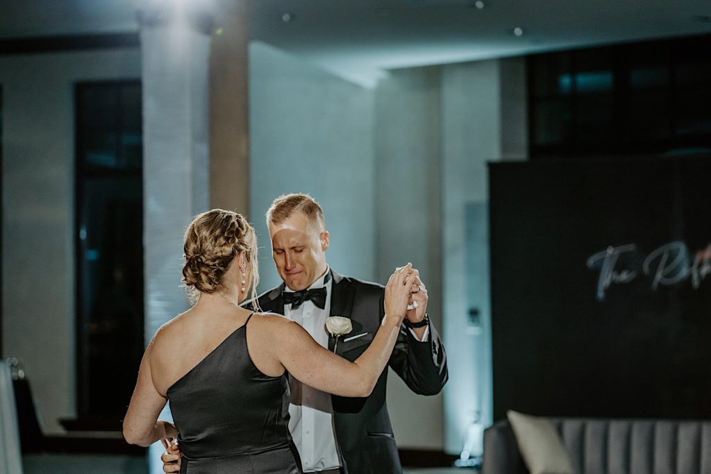 The groom of a wedding tears up as he dances with his mother during his wedding reception.