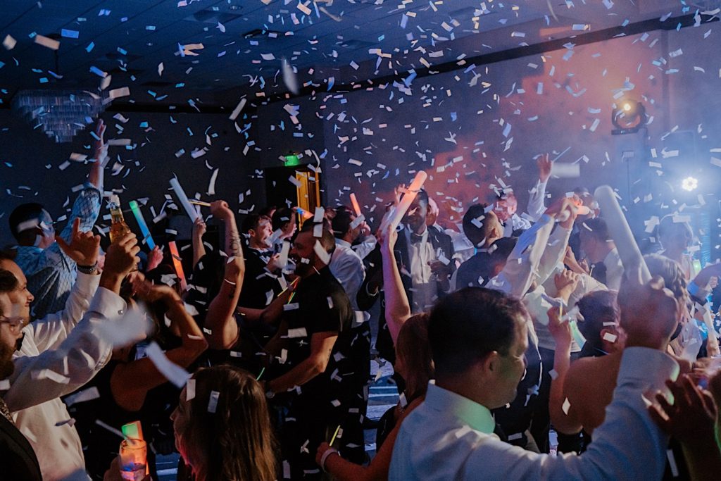 Confetti falls from the ceiling on a group of dancing guests during an intimate indoor wedding reception at Bella Collina in Florida.