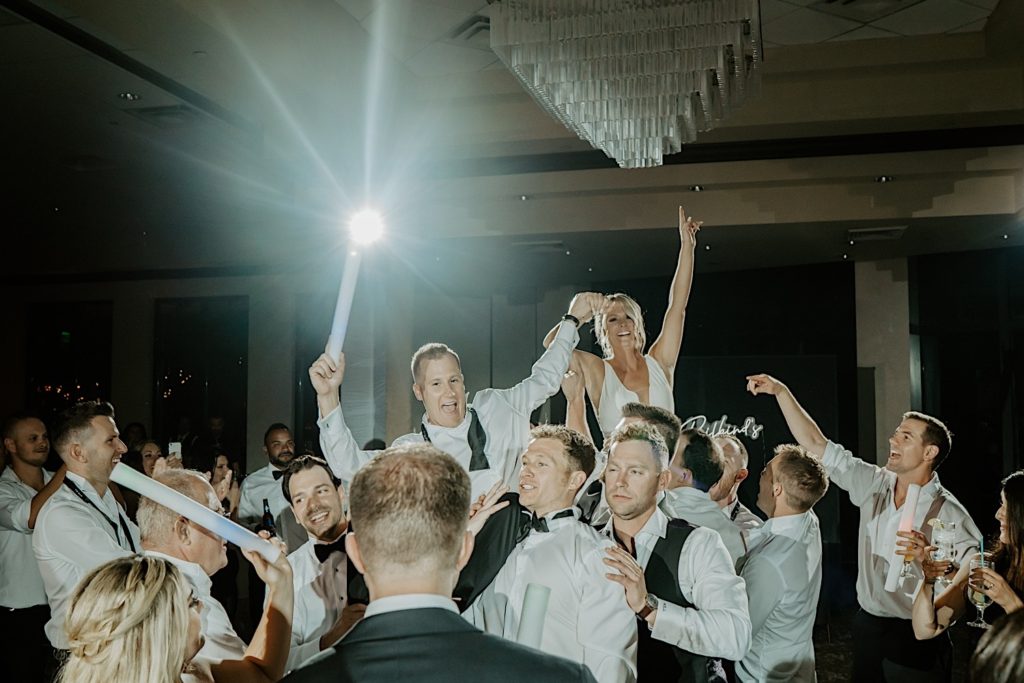A bride and groom are lifted into the air by the groomsmen during their intimate wedding reception at Bella Collina in Florida.