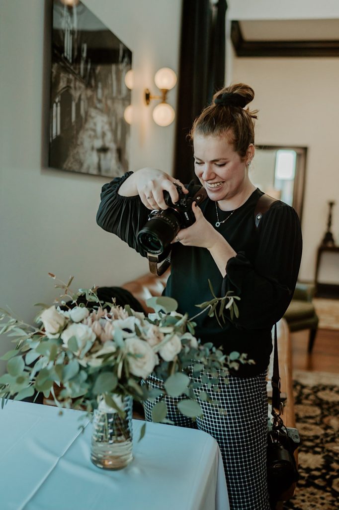 Photograph of Shelby Jane Photography, an Indiana elopement photographer, smiling as she photographs flowers on a table