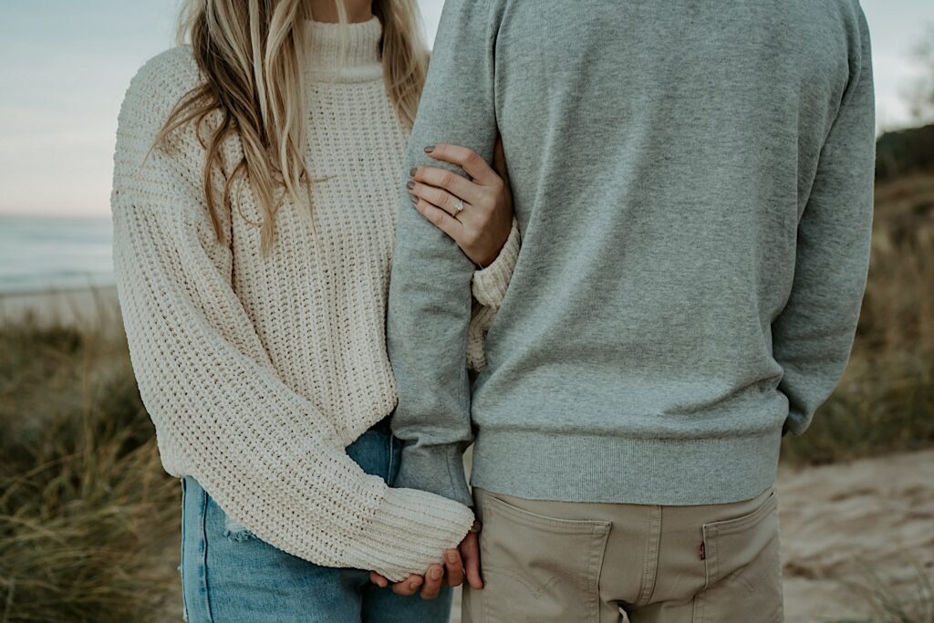 A close up image highlighting the an engaged couples engagement ring and their cozy fall sweaters for their fall Indiana engagement session.