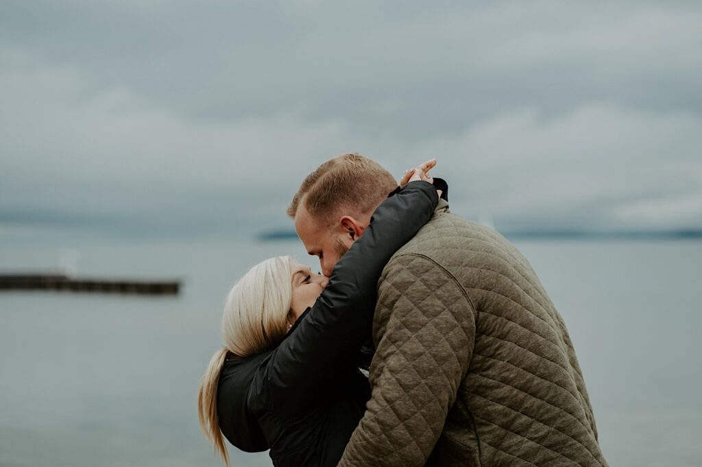 fiancés kiss after their proposal on a Lake Michigan beach in the fall