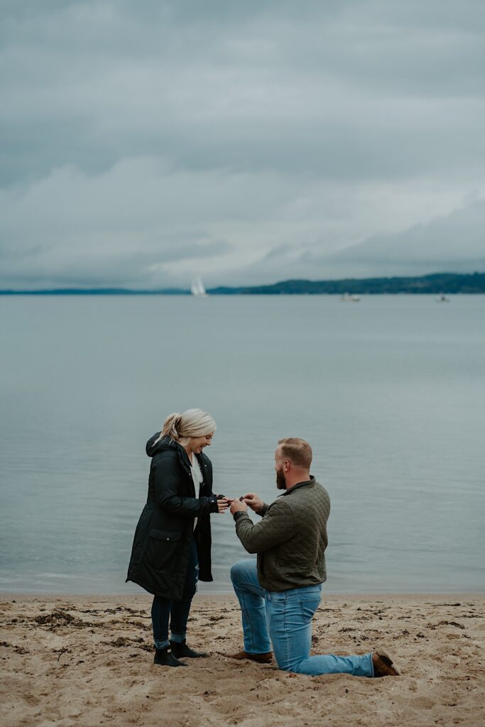 A man proposes to his girlfriend on a beach overlooking Lake Michigan