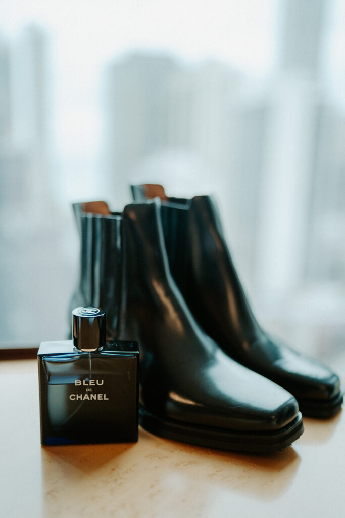A pair of black chelsea boots and a container of Bleu Chanel perfume for one of the brides on their wedding day.