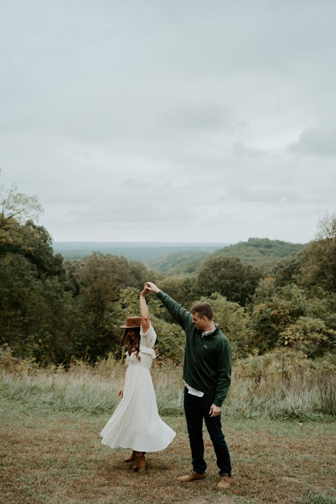 A fiancé twirls his fiancée overlooking a scenic view in Brown County State Park