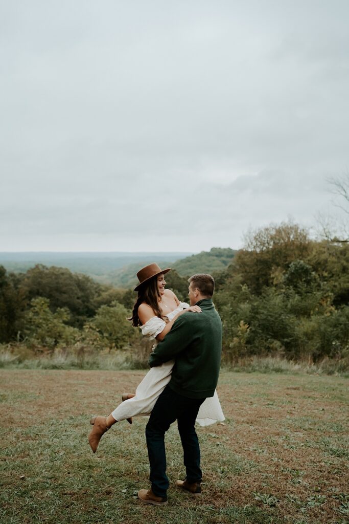 A fiancé hugs and lifts his soon to be wife and twirls her during their engagement session at Brown County State Park.