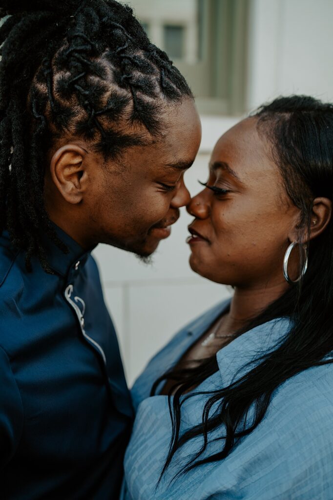 A close up image of a couple holding each other tight and smiling during their engagement session outside a building in downtown Indianapolis.