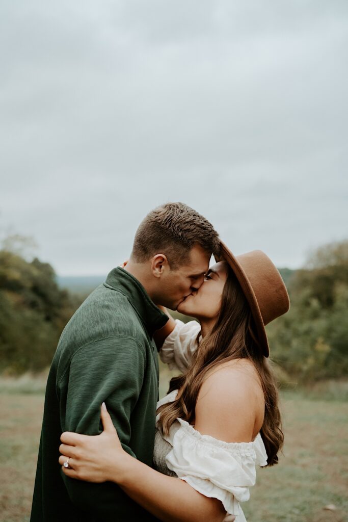 Fiancé's kiss while holding each other tight during their engagement session at Brown County State Park in Indiana.  
