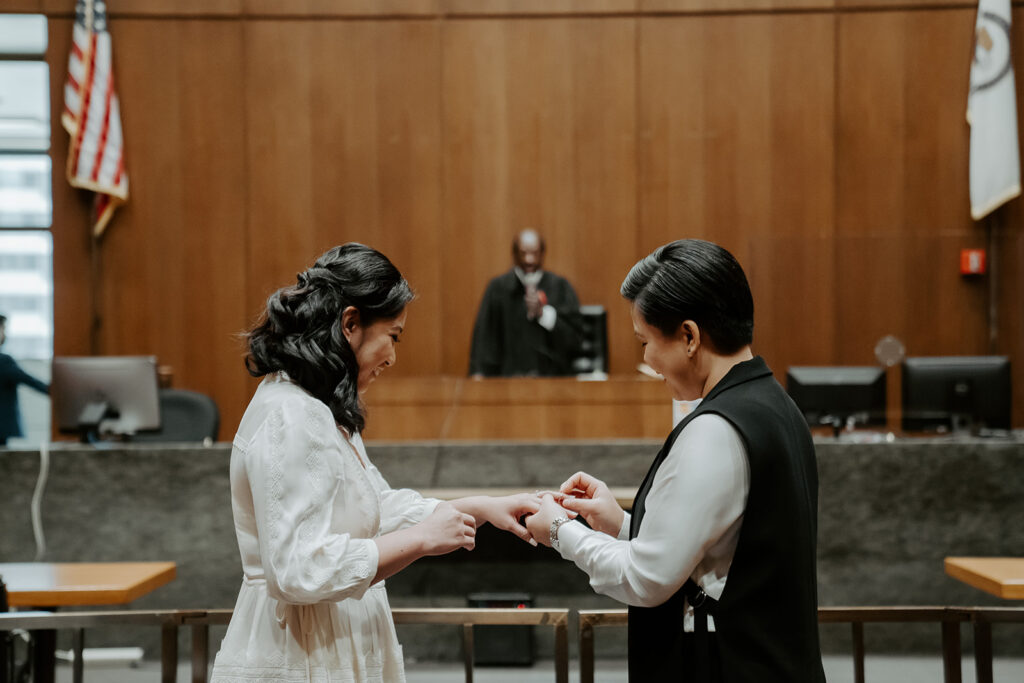 Brides exchange rings during their wedding ceremony at the Cook County Courthouse.