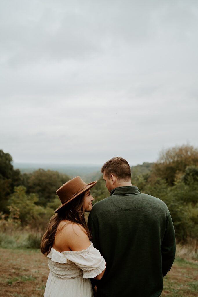 Fiancé's hold each other tight while smiling and looking at one another walking through Brown County State Park.