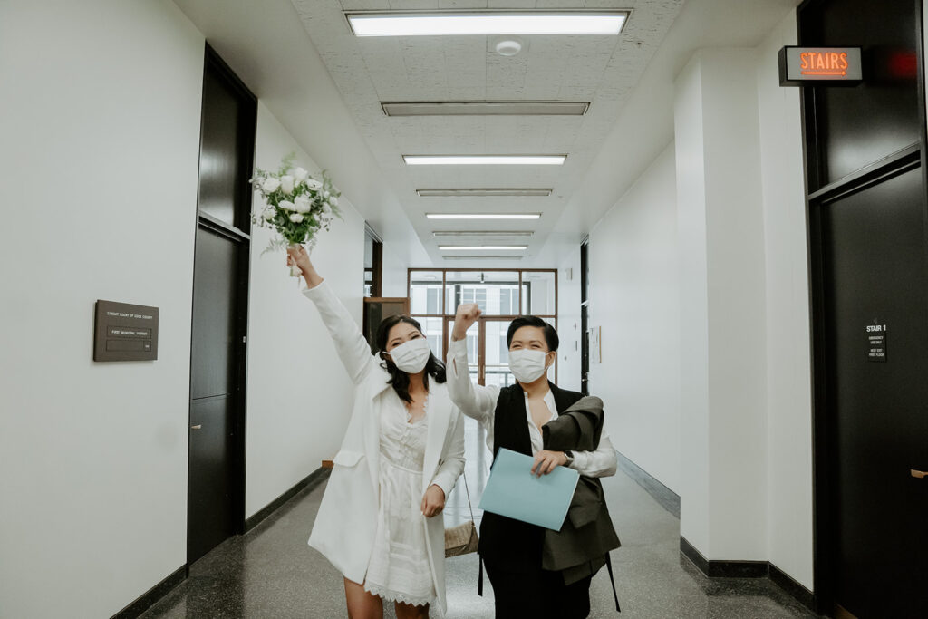 Brides celebrate while walking out of the building after their wedding ceremony at the Cook County Courthouse