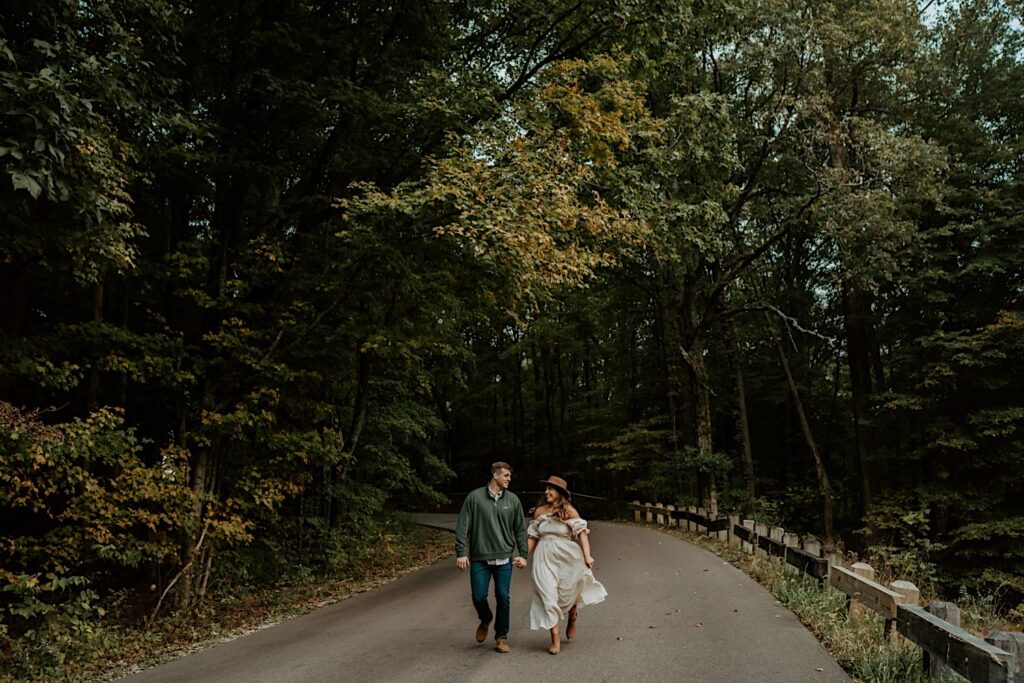 Fiancé's run down a road at Brown County State Park during their Indiana engagement session