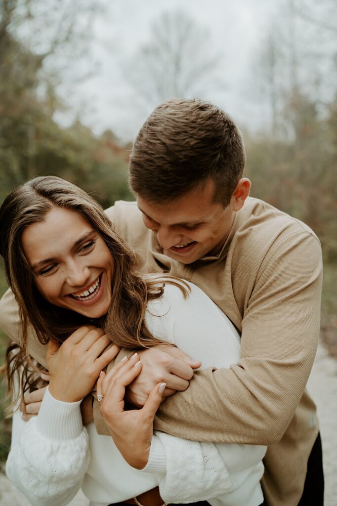 Fiancées hugging during their fall engagement session in a forest in Indiana