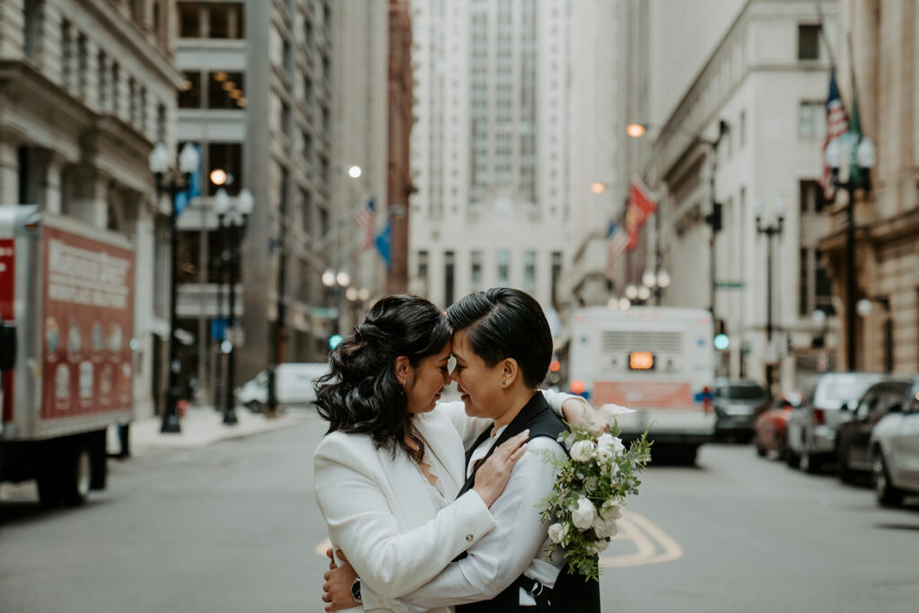 Newly weds stand in the middle of a street in Chicago sharing an intimate moment with one another.  