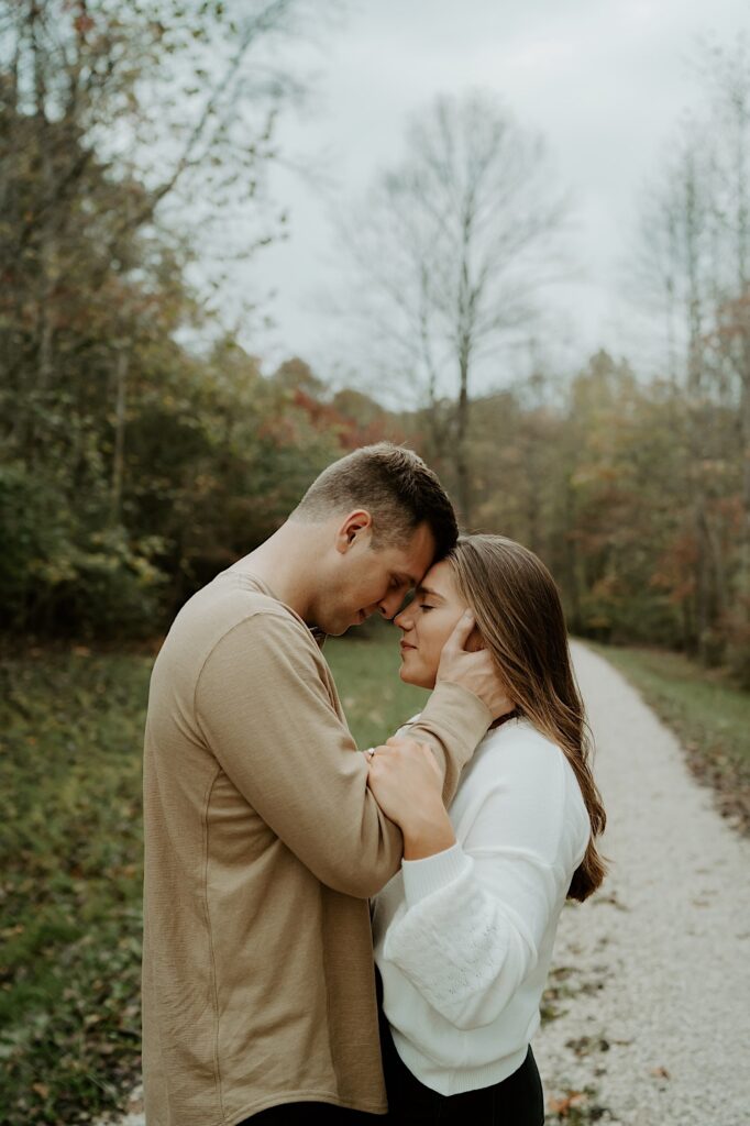 Fiancées hold each other tight and press their foreheads together in a forest in Indiana