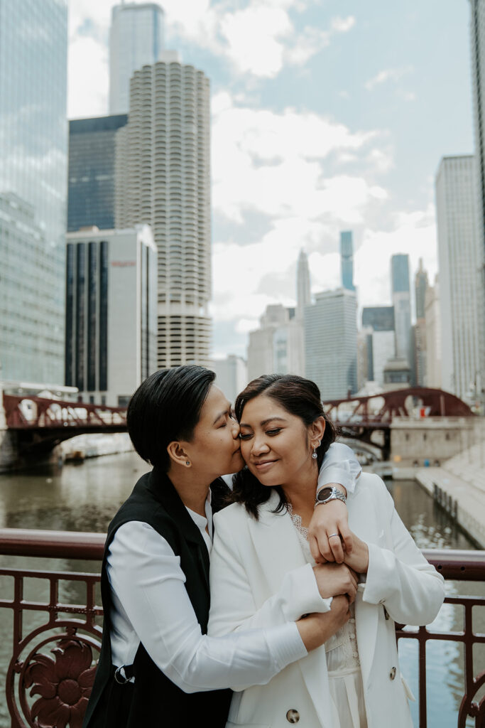 Two brides stand on Dusable bridge during their wedding portraits in the city of Chicago