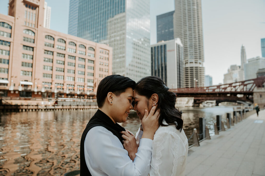 Two brides stand together in front of Merchandise Mart for their wedding portraits.