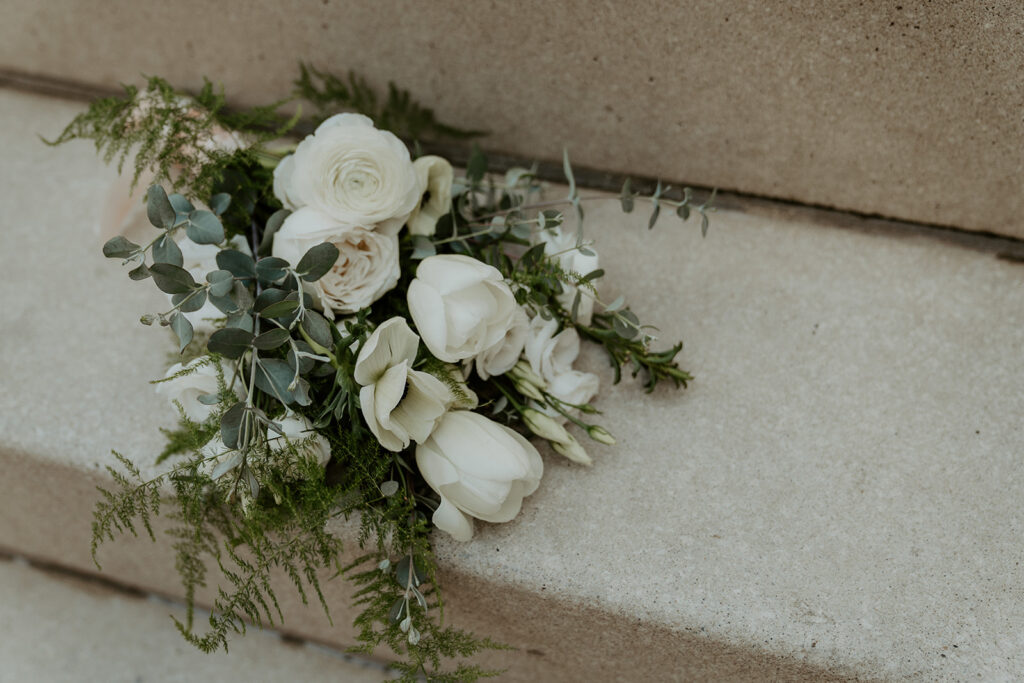 A brides flowers sitting on a concrete step along the riverwalk after their courthouse wedding day.