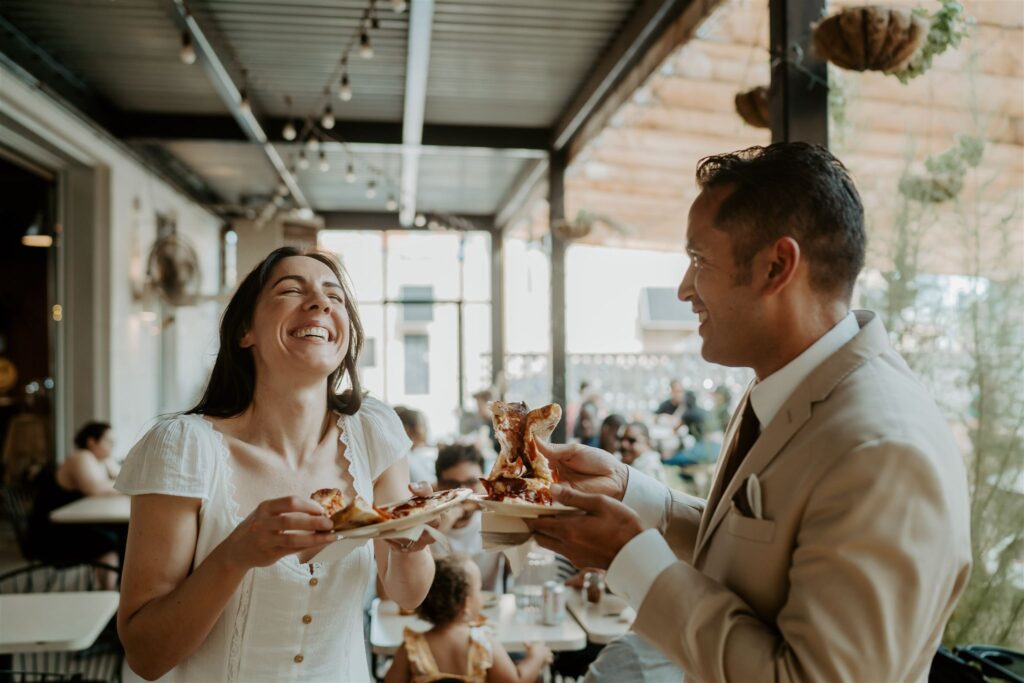 pizza lobo chicago wedding reception elopement reception cutting of the pizza intimate wedding reception laughing couple