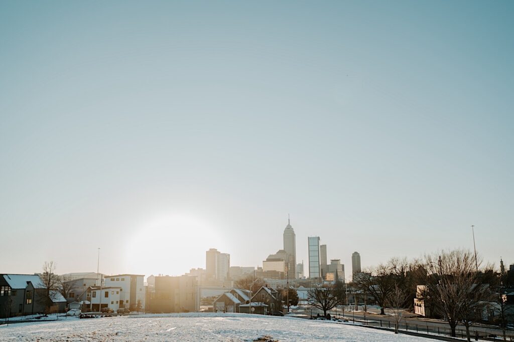 A photo of Indianapolis at sunrise with a snow covered field in the foreground